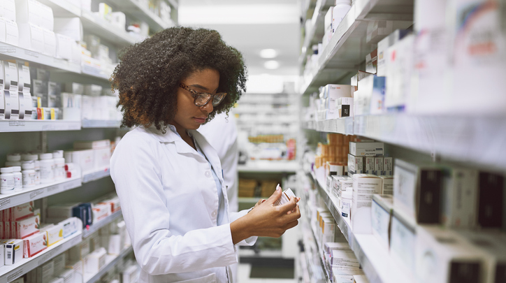 Young Female Pharmacist Stocking Shelves